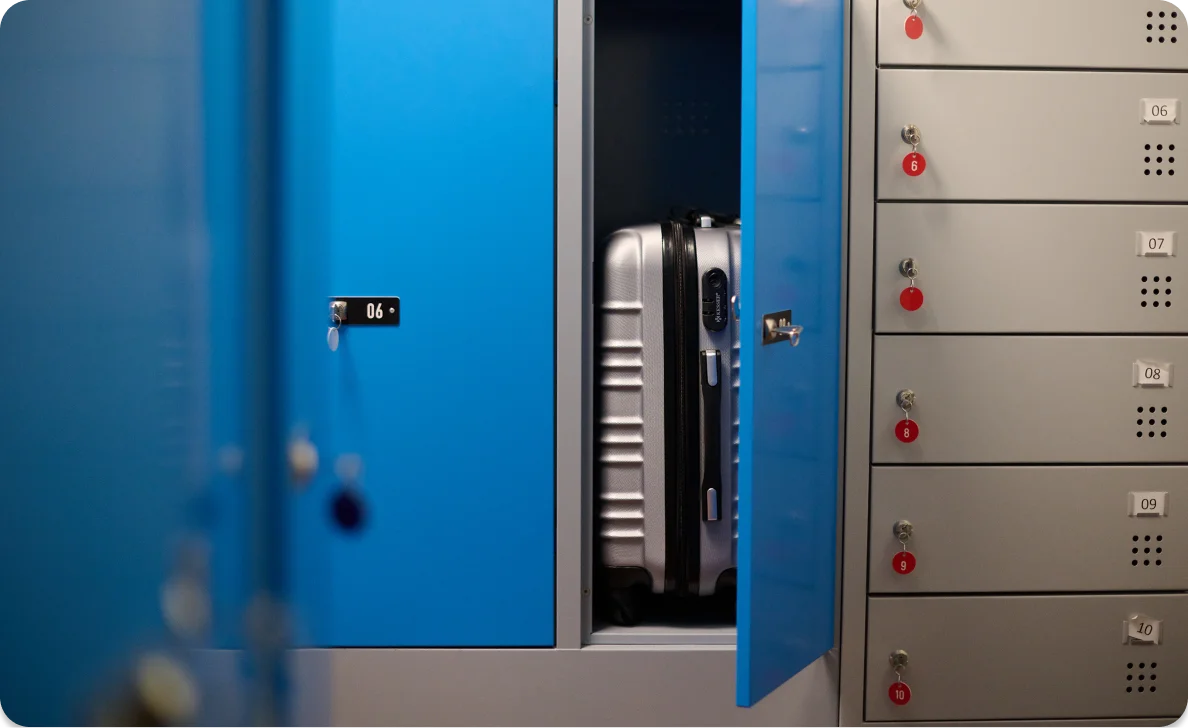 Offener blauer Spind mit Koffer darin, umgeben von weiteren Spinden