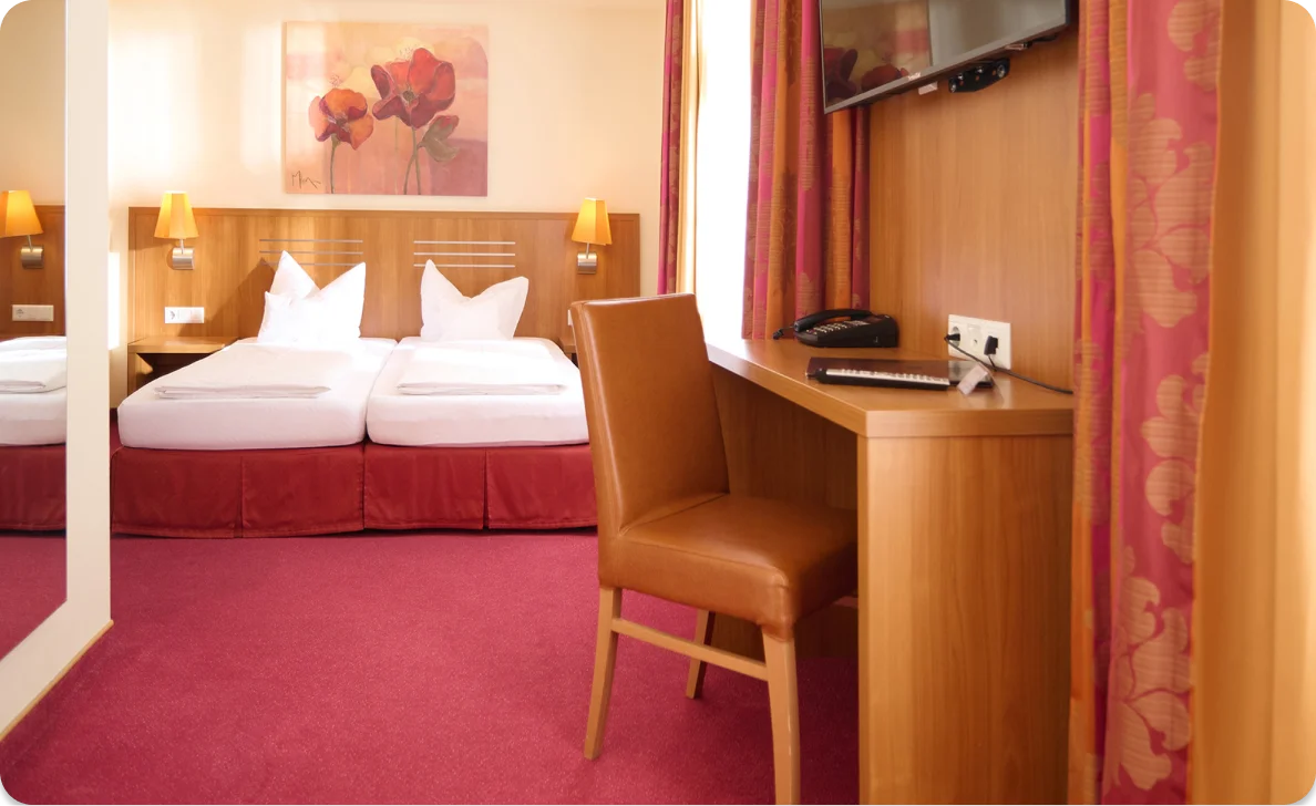 Hotelzimmer mit zwei Betten und Schreibtisch