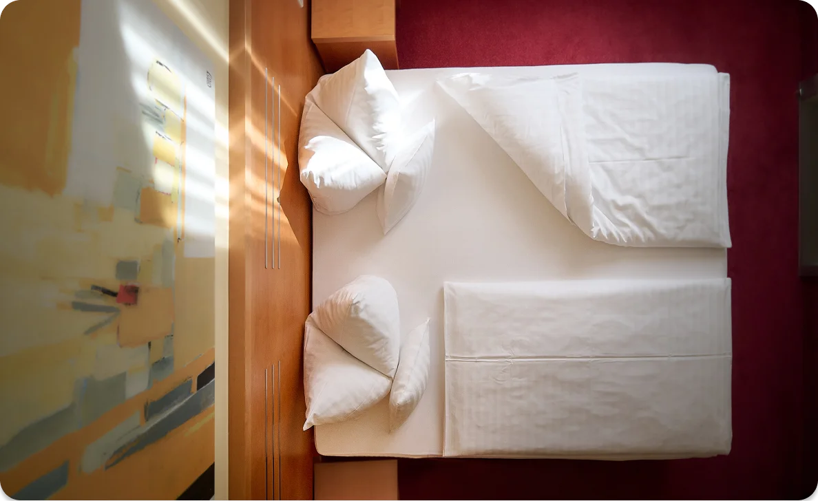 Gemachtes Bett in Hotelzimmer mit weißen Laken und Kissen
